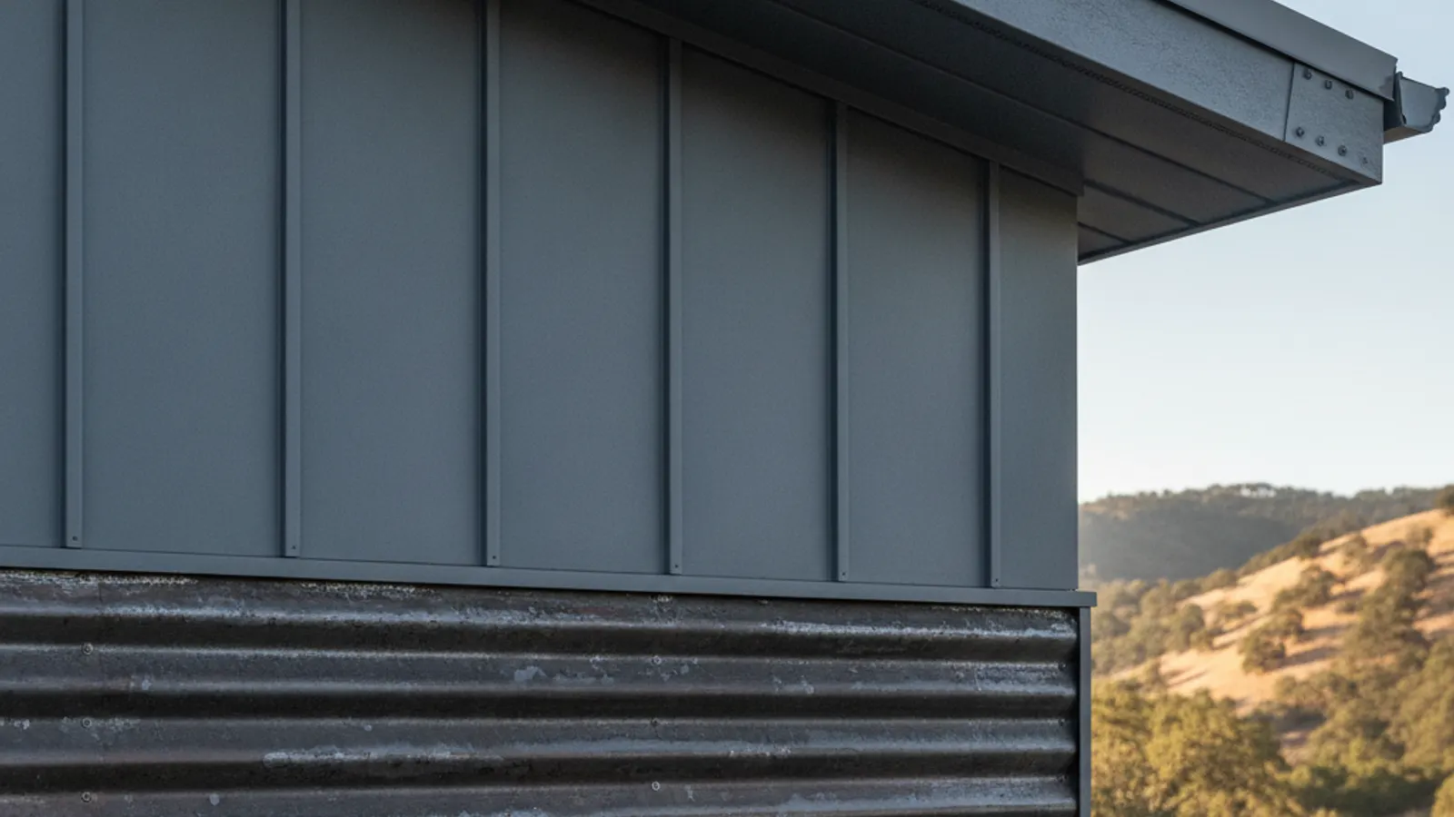 Corrugated and standing-seam metal siding with a closed protected eave on a foothill home
